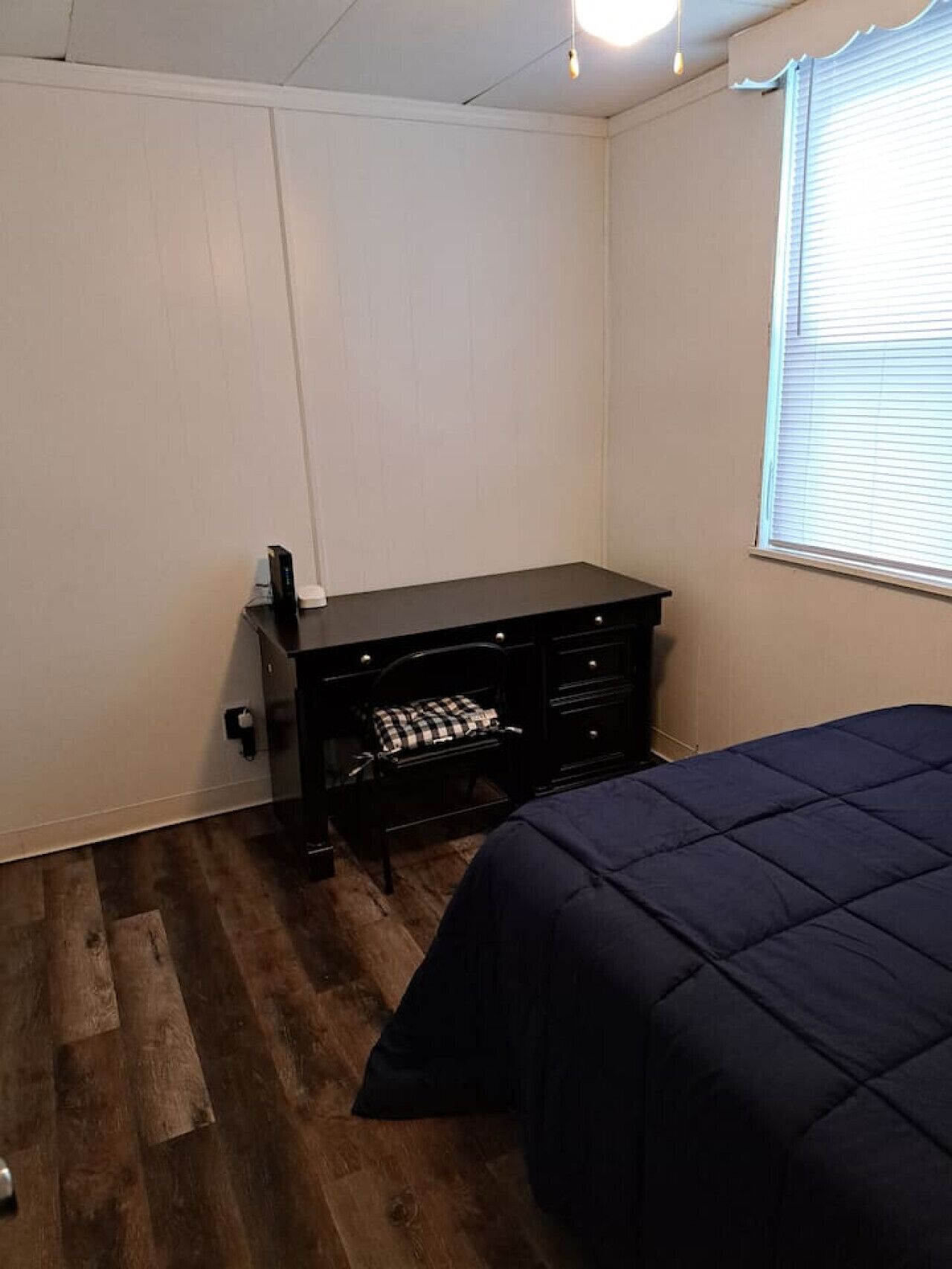 A bedroom with a bed, a desk, and a chair.