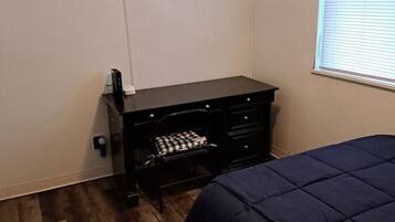 A bedroom with a bed, a desk, and a chair.