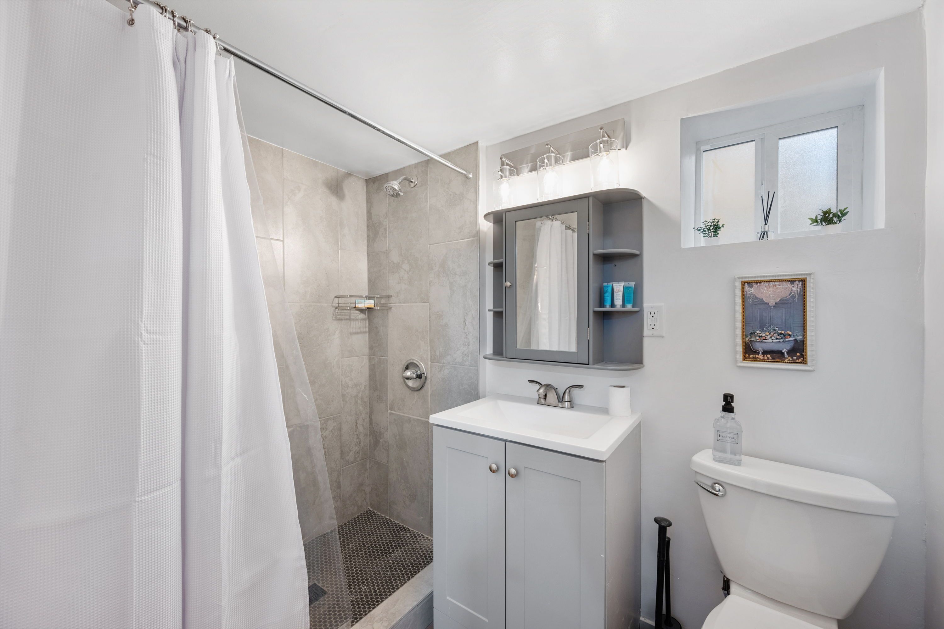 A modern bathroom with a shower, toilet, and vanity.