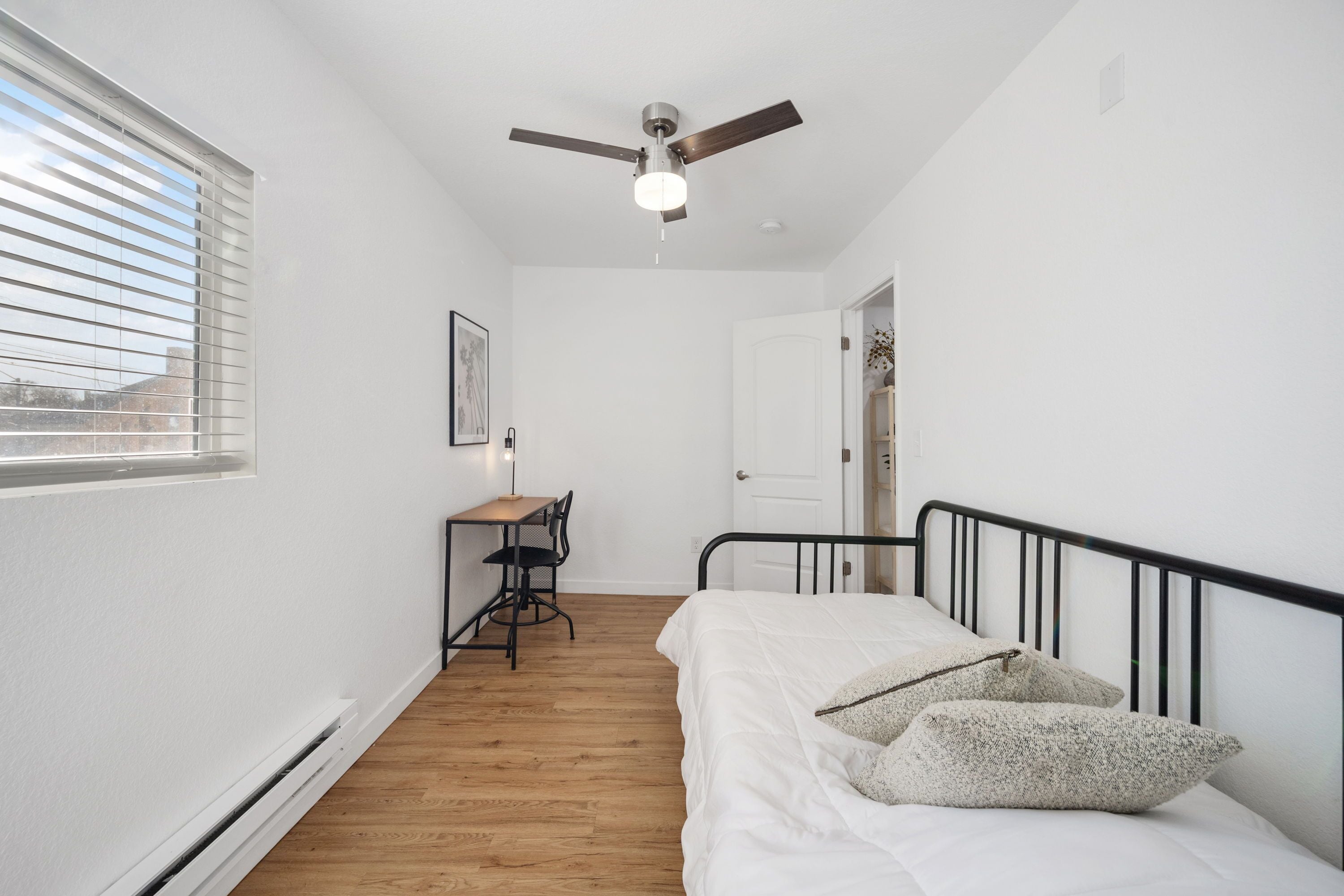 Une chambre à coucher avec un lit, un bureau et un ventilateur de plafond.