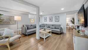 Un salon moderne avec un canapé gris, une table basse en bois et un fauteuil blanc.