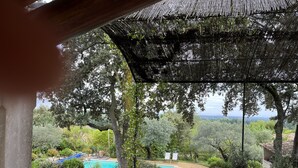A patio with a table and chairs overlooking a swimming pool, surrounded by lush greenery and trees. - Maison sur la Colline, Lagnes Proche de Gordes et Lisle sur la Sorgue (Lagnes)