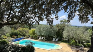 A swimming pool surrounded by trees and greenery, with a view of the landscape. - Maison sur la Colline, Lagnes Proche de Gordes et Lisle sur la Sorgue (Lagnes)