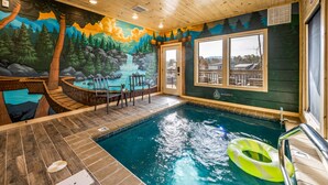 Un área de piscina con un mural, un jacuzzi y vista a una casa.