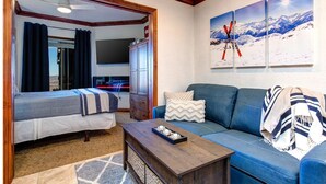A bedroom with a bed, a dresser, a blue sofa, and a coffee table. - Westgate 8th Floor Remodeled Luxury Studio Suite- Ski-In/Out, Full Kitchen (Park City)