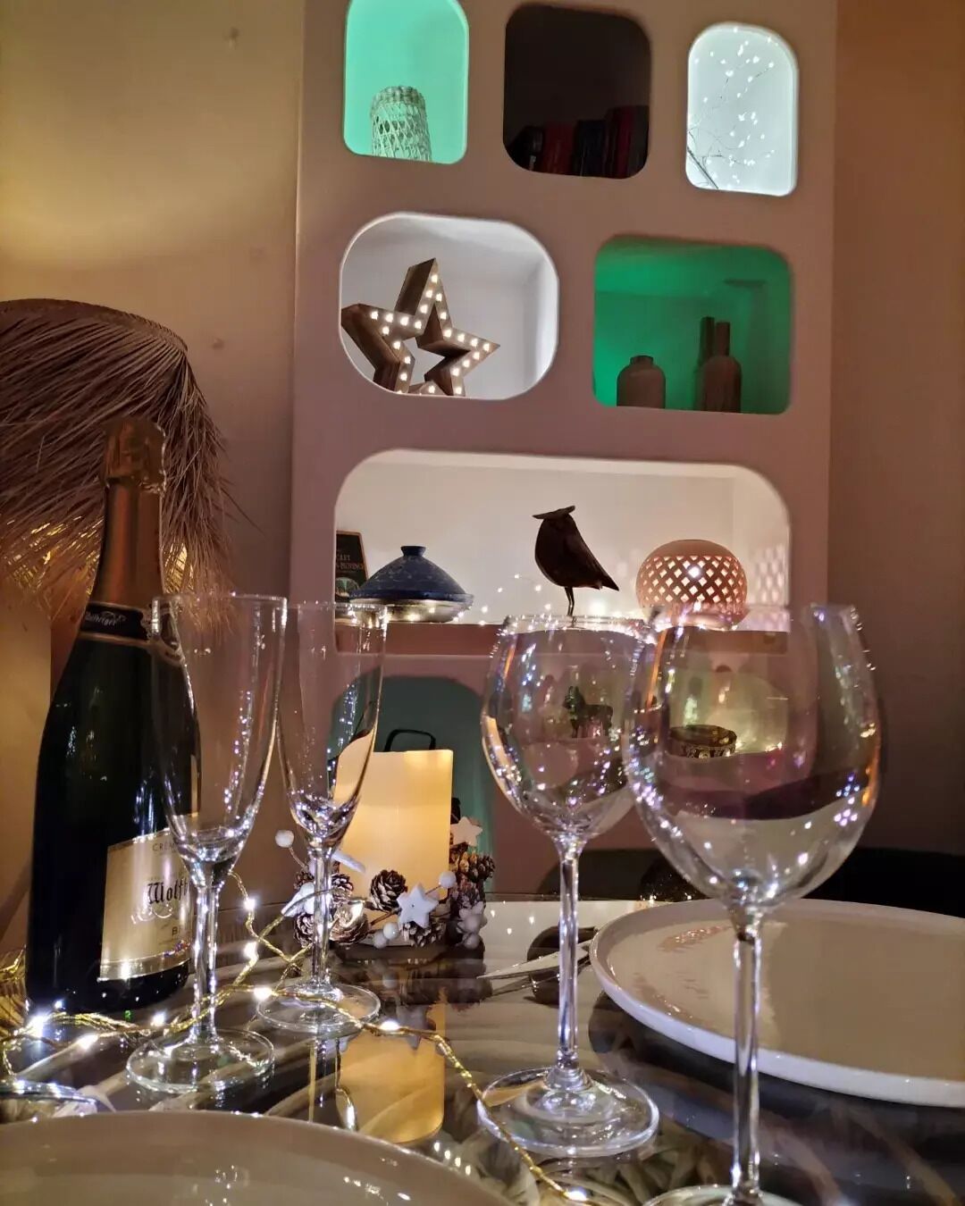 Une table dressée avec des verres à vin, une bouteille et des objets décoratifs.