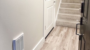 A hallway with a wooden door, a staircase, and a sign that reads "stay alive but not too long." - Beautiful, newly built 4 bedroom with garage (Yakima)