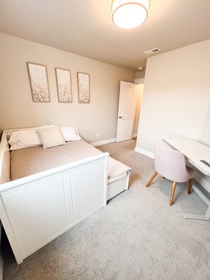 Un dormitorio con cama, escritorio y puerta.