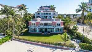 A multi-story hotel with a central courtyard, surrounded by palm trees and a sandy beach. - Renovated Beachfront 3 BR - Steps to Baha Mar (Nassau)