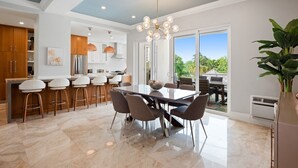 A modern kitchen with a bar area, large windows, and a dining space with a view. - Renovated Beachfront 3 BR - Steps to Baha Mar (Nassau)