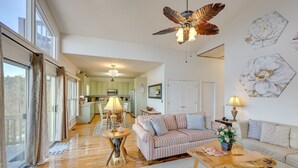 A spacious living room with a large window, a ceiling fan, and a kitchen in the background. - Blue Ridge Mountain Resort Home with Amazing Views at Olde Beau -Mountain escape (Glade Valley)