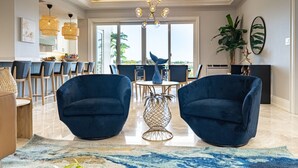 A modern living room with two blue armchairs, a round coffee table, and a chandelier. - Luxe 3 BR: Beachfront Suite Next to Baha Mar (Nassau)