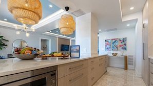 A modern kitchen with a large island, built-in appliances, and decorative wicker lighting. - Luxe 3 BR: Beachfront Suite Next to Baha Mar (Nassau)