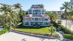 A multi-story hotel with a central courtyard, surrounded by palm trees and a sandy beach. - Luxe 3 BR: Beachfront Suite Next to Baha Mar (Nassau)