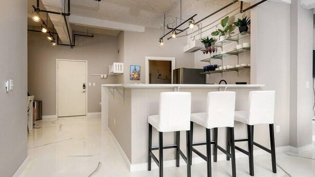 Une cuisine moderne dotée d’un îlot central, de tabourets de bar et de luminaires suspendus.