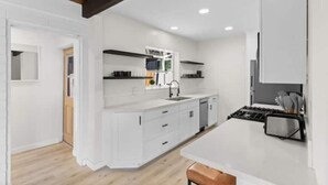 A modern kitchen with white cabinetry, a wooden ceiling, and a central island. - Cozy, bright, and walk to Crown Point Park/Bay (San Diego)