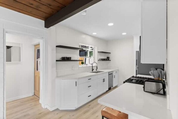 Une cuisine moderne avec des meubles blancs, un plafond en bois et un îlot central.