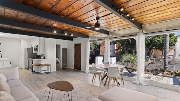 A spacious living area with a wooden ceiling, a kitchen in the background, and a patio with outdoor seating. - Cozy, bright, and walk to Crown Point Park/Bay (San Diego)