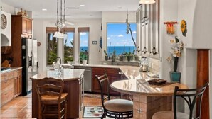 A spacious kitchen with a large island, wooden cabinets, and a view of the ocean.