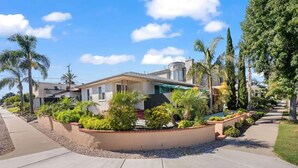 A residential house with a landscaped garden, a curved driveway, and a clear blue sky. - Cozy, home with hottub & patio! (Los Angeles)