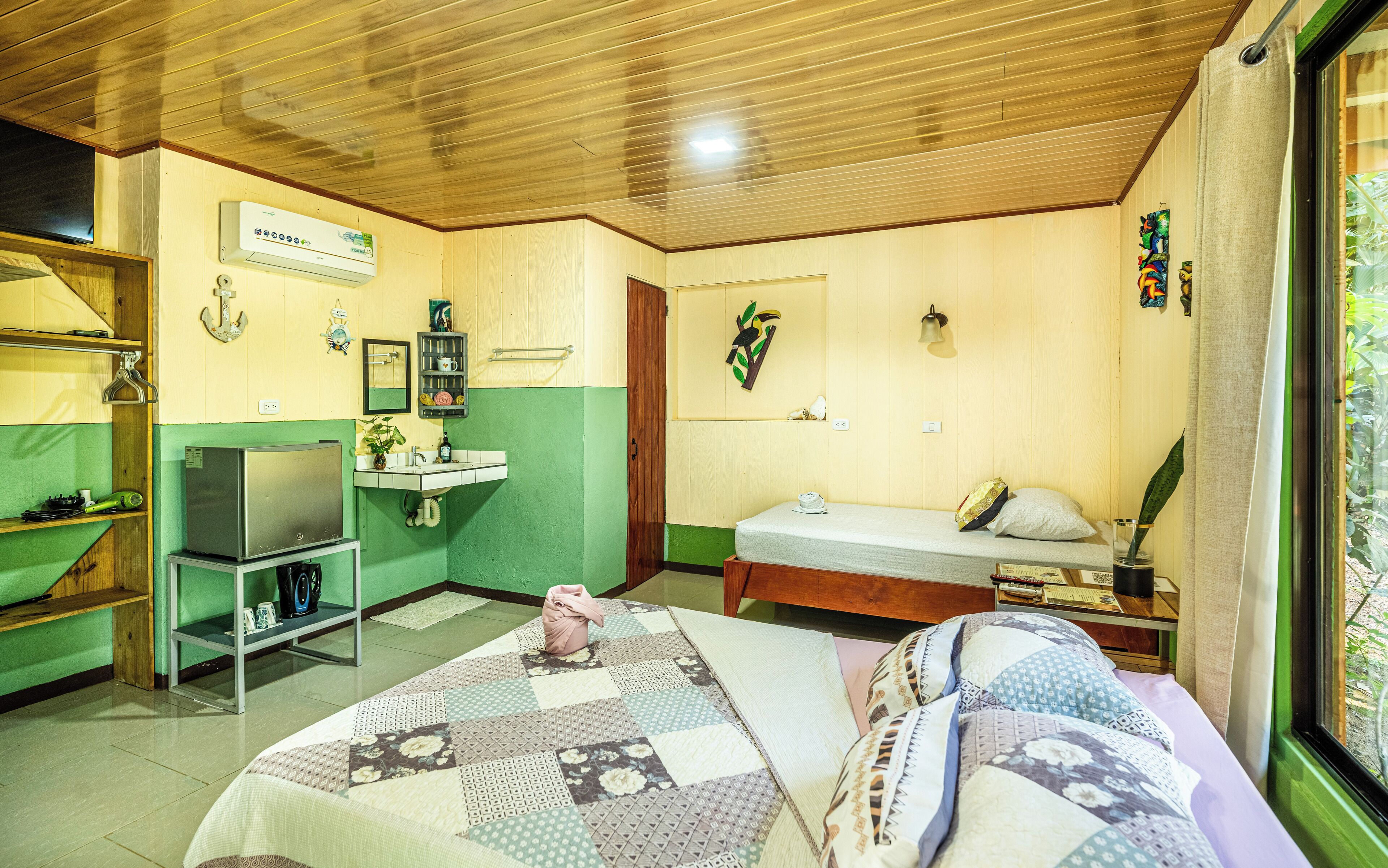 Una habitación compacta con cama, un pequeño escritorio, un lavabo y un espejo.