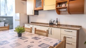 A kitchen with wooden cabinets, a granite countertop, and a dining table with a nautical-themed tablecloth. - SE032 - Senigallia, comfortable four-room apartment 30 meters from the sea (Senigallia)