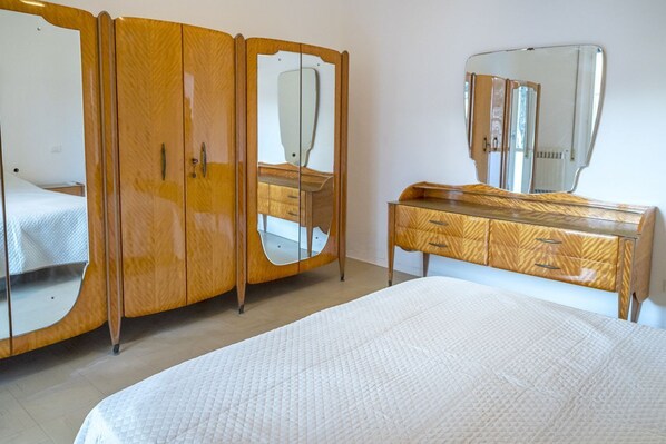 A bedroom with a bed, a wooden wardrobe with mirrors, and a dresser.