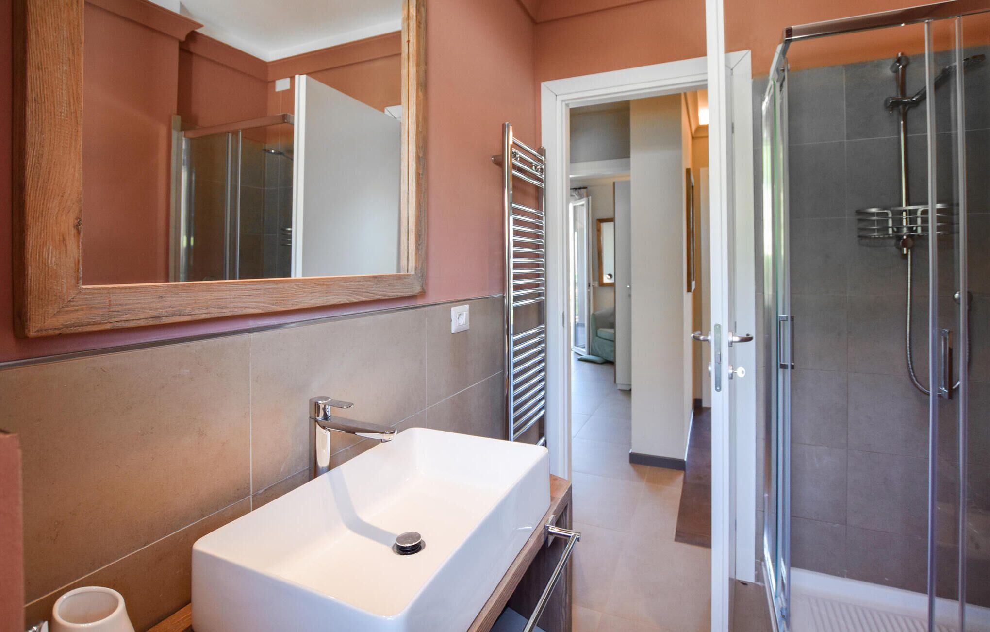 Une salle de bain avec un lavabo blanc, un miroir et une douche en verre.