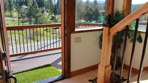 A wooden staircase with a railing leading to a balcony with a view of a road and trees. - Castle Cabin - A Spacious Tahoe Retreat. (South Lake Tahoe)