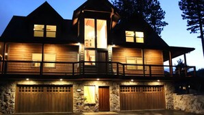 A two-story house with a stone facade, a balcony, and two garage doors. - Castle Cabin - A Spacious Tahoe Retreat. (South Lake Tahoe)