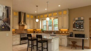 A spacious kitchen with a large island, white cabinetry, and a central island bar. - Castle Cabin - A Spacious Tahoe Retreat. (South Lake Tahoe)