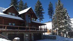 A wooden lodge with a balcony, surrounded by snow-covered trees and a mountain backdrop. - Castle Cabin - A Spacious Tahoe Retreat. (South Lake Tahoe)