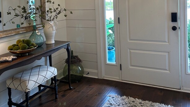A hallway with a white door, a mirror, a bench, a vase with green balls, and a hanging light fixture. -  Pet friendly with community pool! (St. Simons Island)