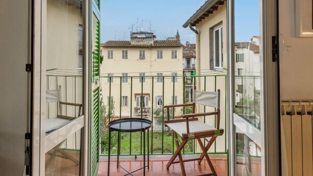 Un balcon donnant sur un immeuble, une petite table et une chaise.