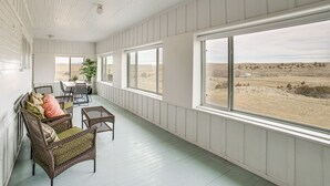 A covered porch with wicker furniture, large windows, and a view of a dry landscape. - Secluded Montana Getaway w/ Fire Pit & Views! (Ryegate)
