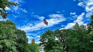 A flagpole with an American flag, surrounded by trees and a building in the background.