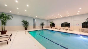 A swimming pool with lounge chairs and potted plants.