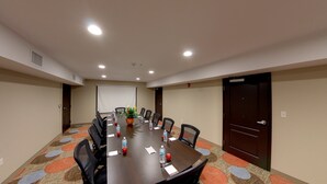 A conference room with a long table, chairs, a projector screen, and a door.
