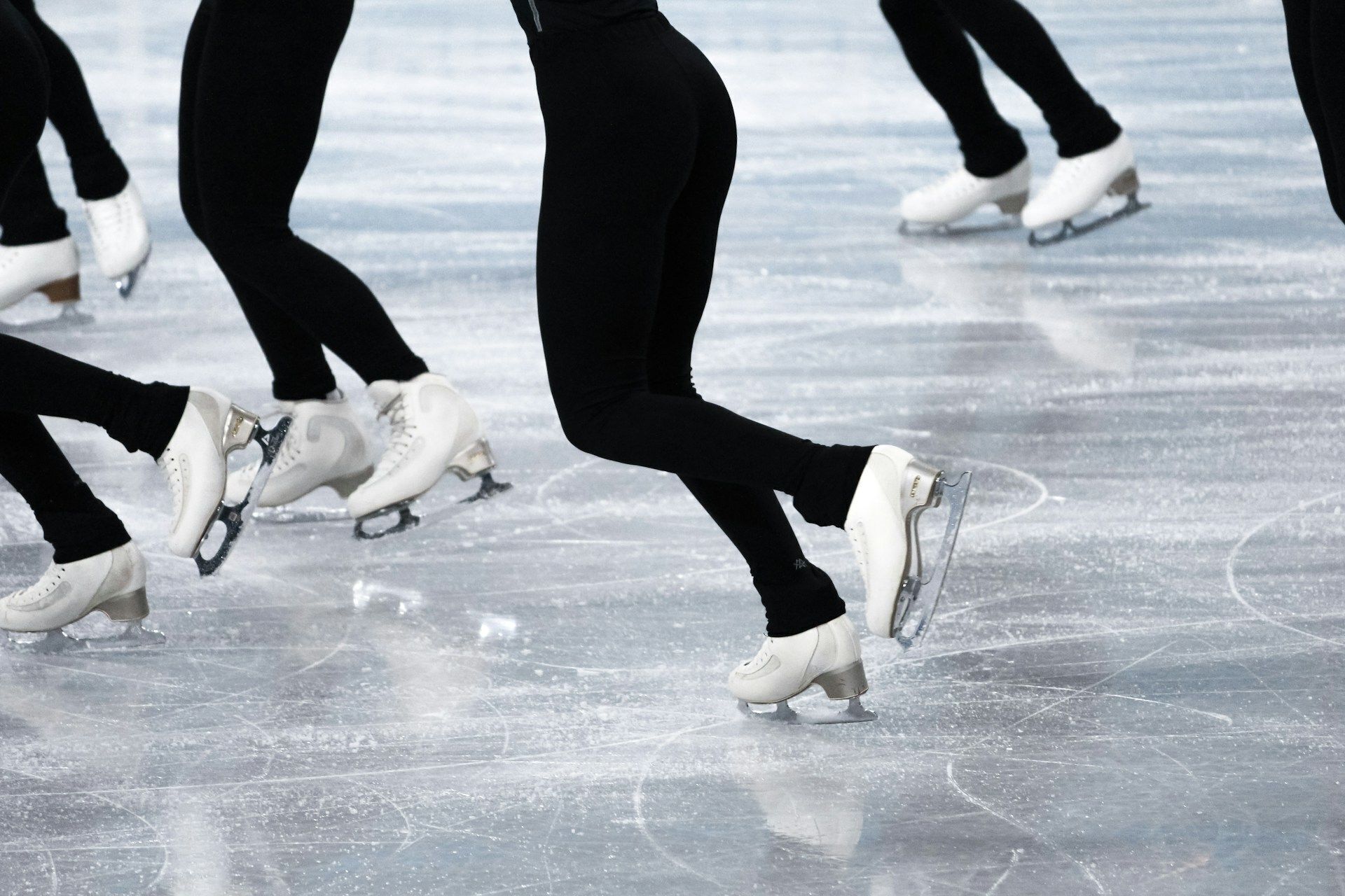Primer plano de patinadores sobre hielo vestidos de negro en una pista de hielo.