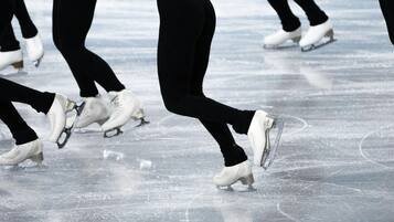 Primer plano de patinadores sobre hielo vestidos de negro en una pista de hielo.