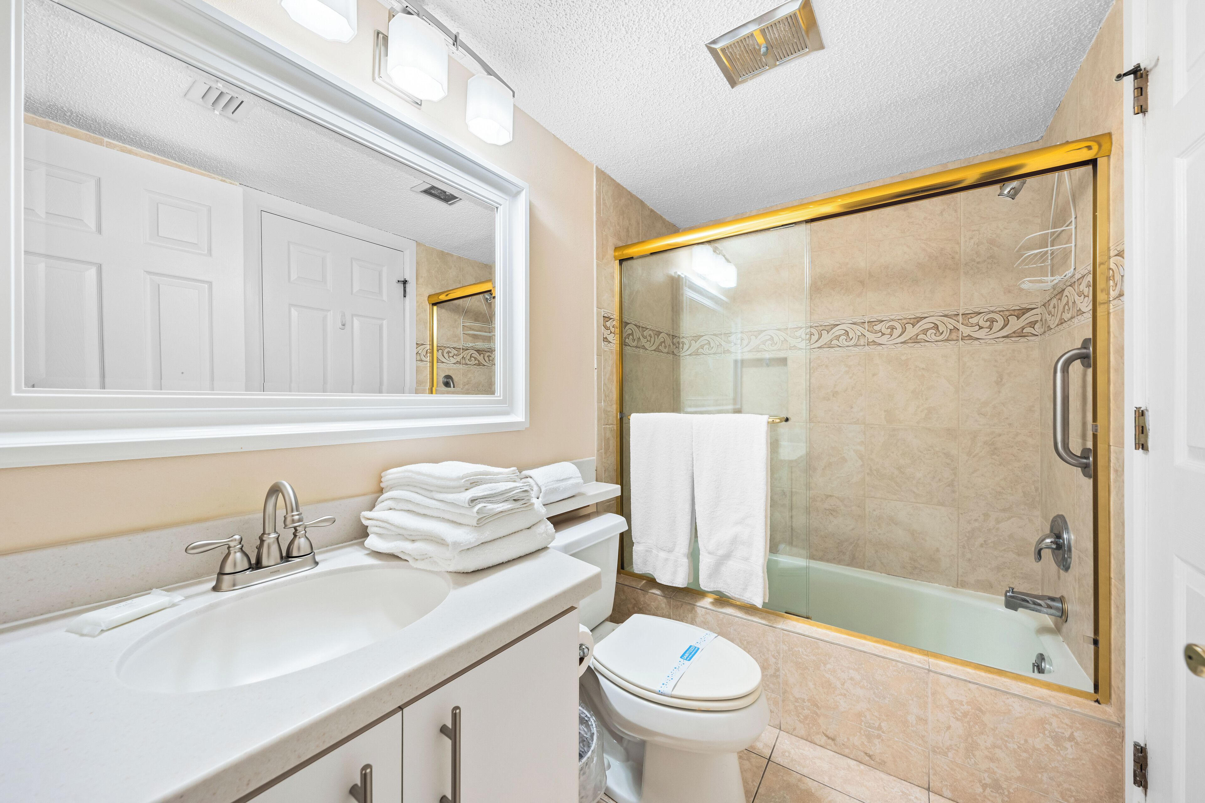 Un baño con lavamanos, inodoro y ducha con mampara de vidrio.