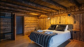 A log cabin-style bedroom with a wooden bed, a nightstand, and a lamp.