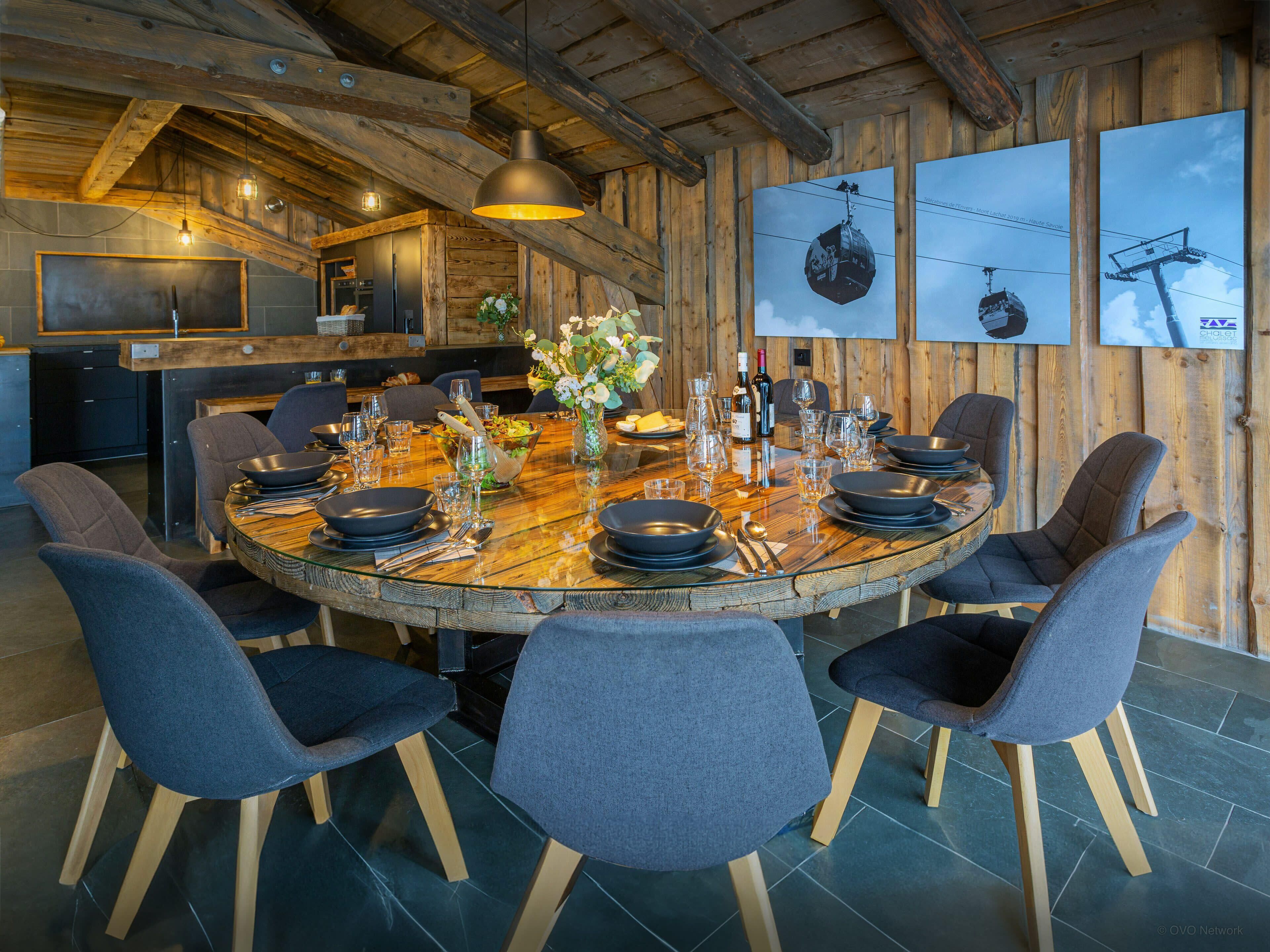 Een houten interieur met een ronde eettafel voor zes personen, omringd door zes stoelen.