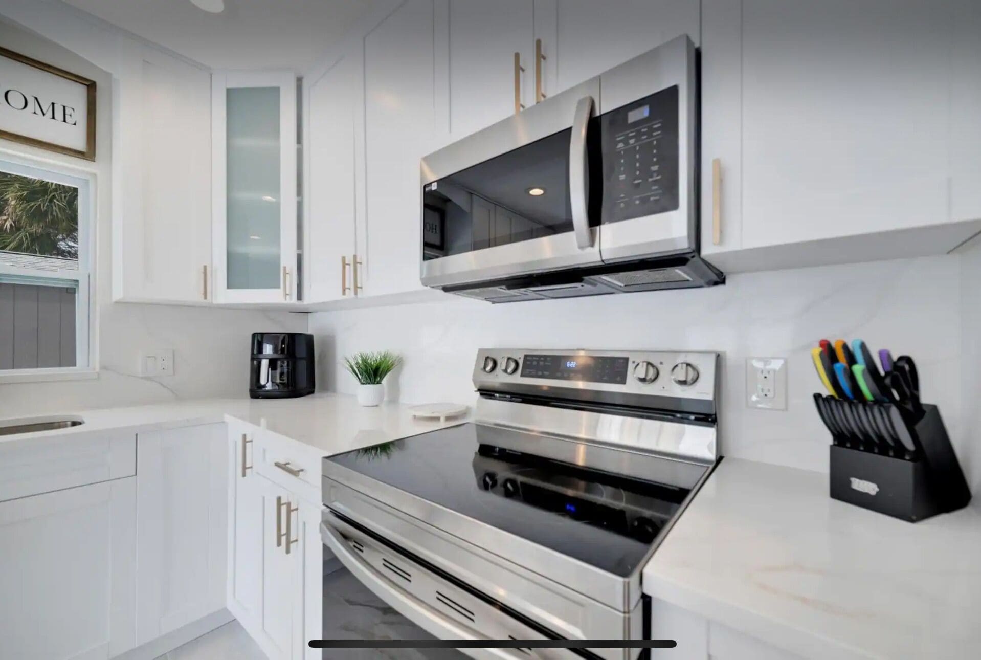 A modern kitchen with white cabinetry, stainless steel appliances, and a coffee maker.