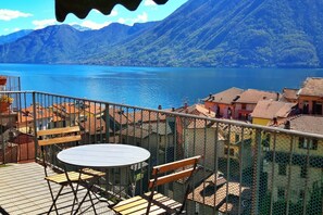 A balcony with a table and chairs overlooking a lake and mountains. - Lake View Gateway - My Home In Como (Argegno)