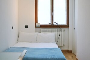 A bedroom with a bed, a radiator, and a window.