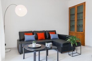 A modern living room with a sectional sofa, two coffee tables, a floor lamp, and a cabinet with glass doors.