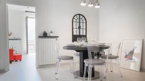 Un espace repas moderne avec une table ronde, des chaises transparentes et une fenêtre à cadre noir.