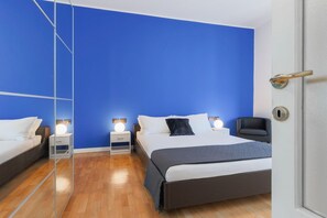 A bedroom with a large bed, bedside tables, a chair, and a mirror.
