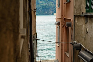 Un callejón estrecho con vistas a una masa de agua y un edificio con balcón.